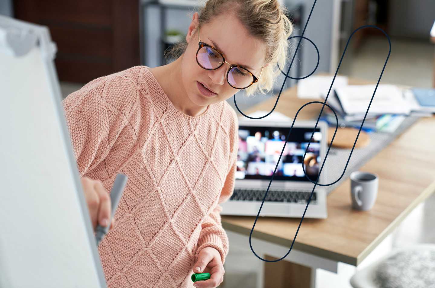 a woman writing on a whiteboard with a laptop in the background