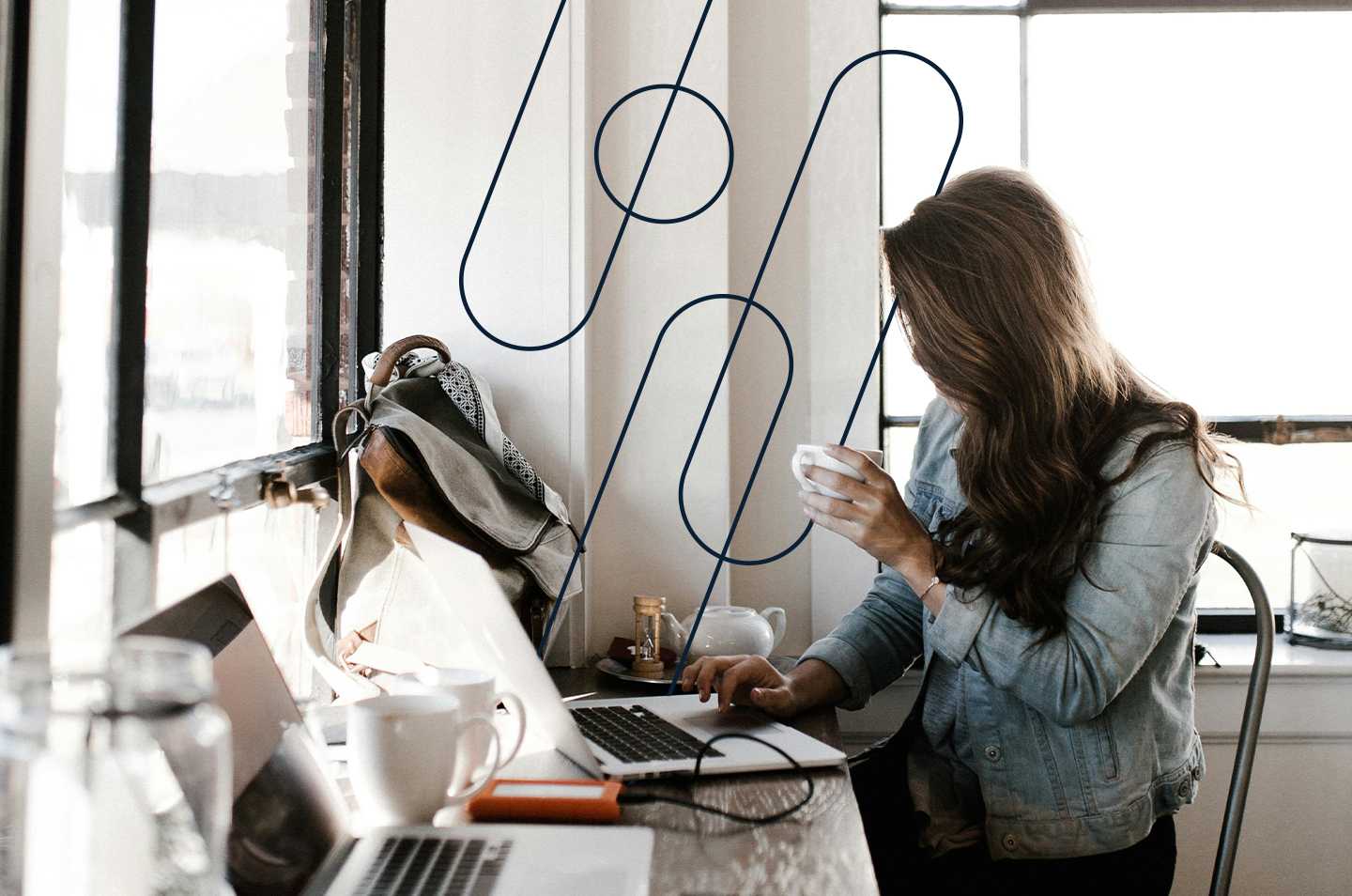 a woman sitting at a workstation drinking from a mug