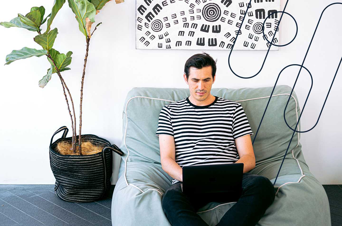 a man sitting on a chair working on a laptop